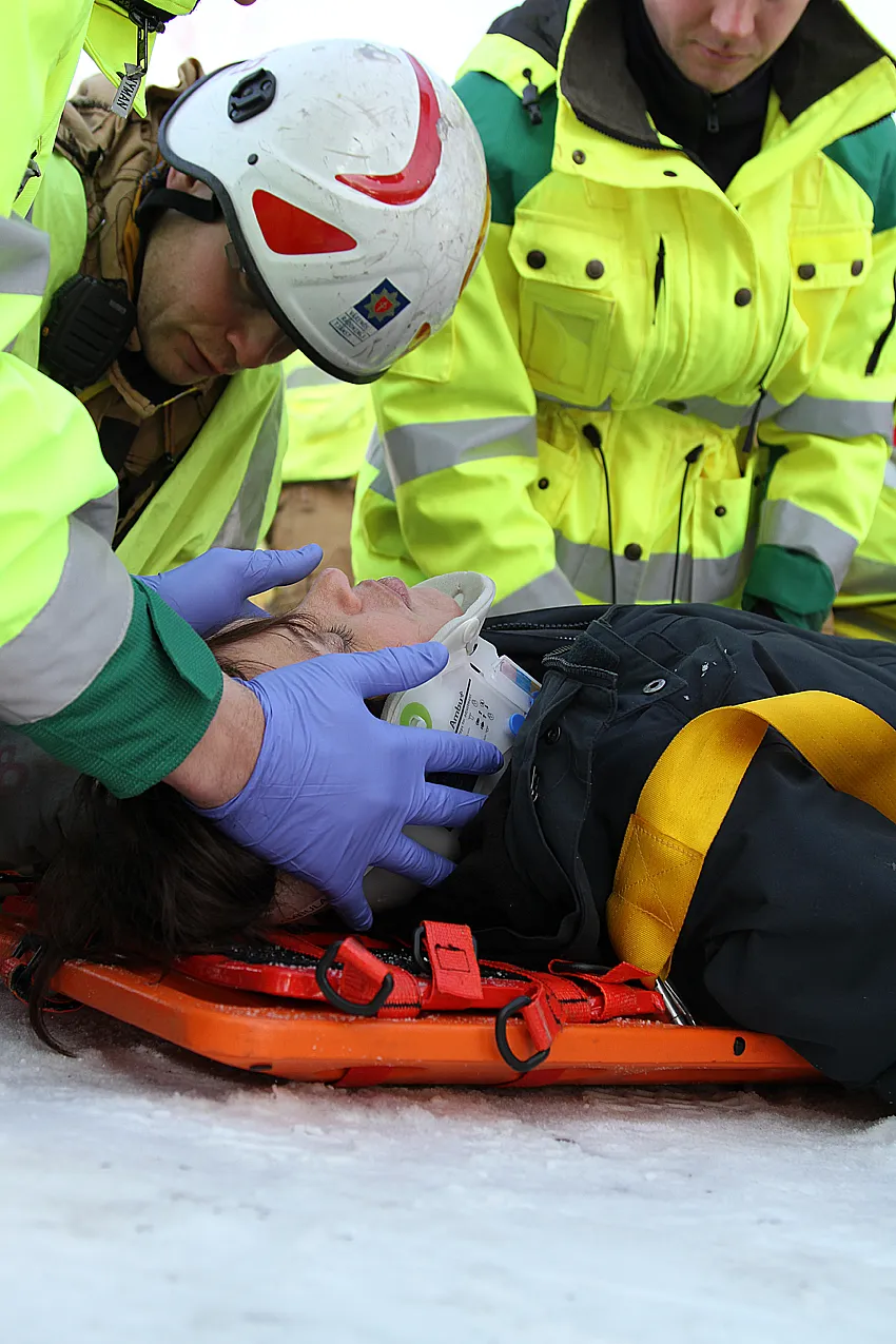 Emergency responders treating patient on spineboard in snow