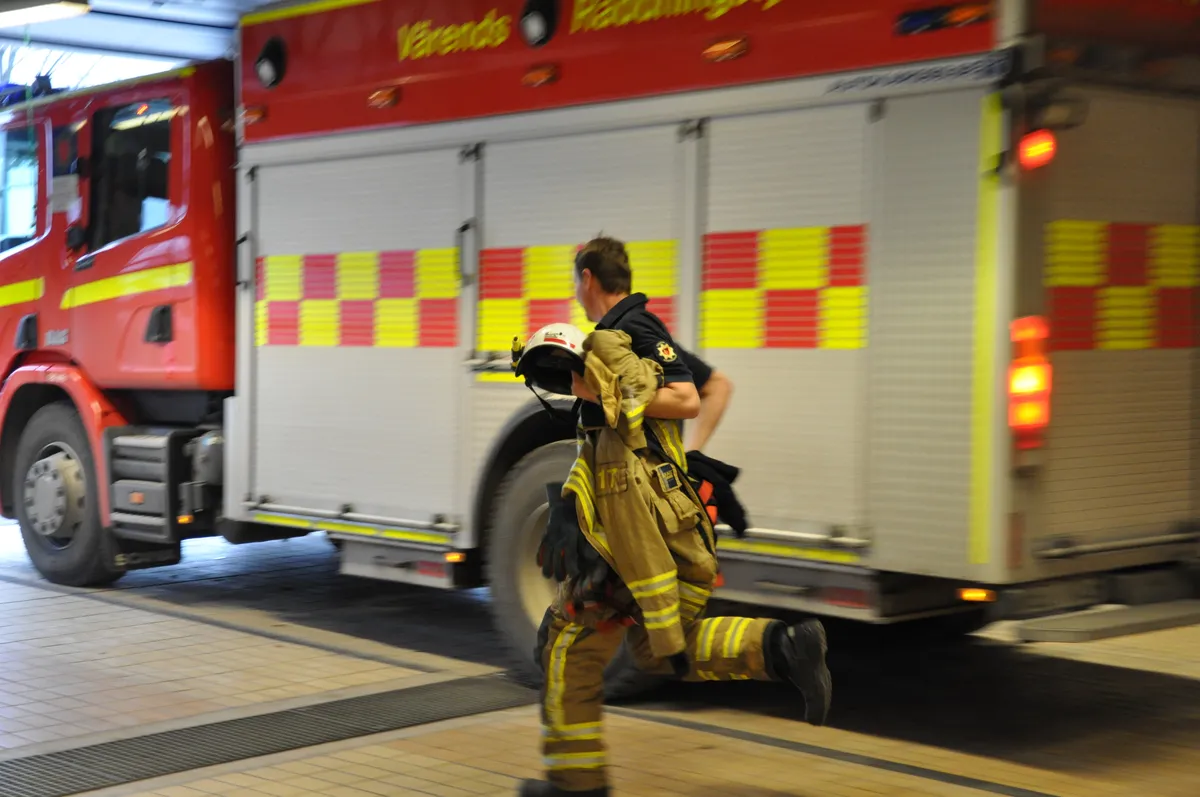 Firefighter running past fire truck in vehicle bay during emergency call